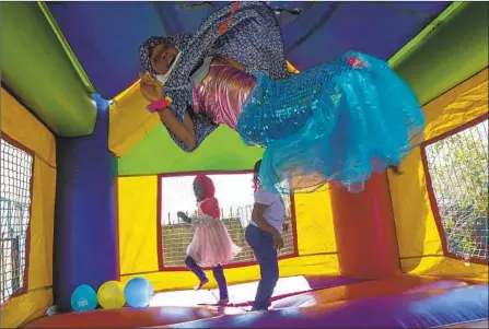  ?? Photograph­s by Irfan Khan Los Angeles Times ?? MIRROR LEWIS, 9, plays in a jumping castle during Eid al-Adha at Masjid Bilal Islamic Center. “The community is on the decline, so we have to put a robust effort towards keeping our youth” and ensuring new Muslims are converted, says Imam Jihad Saafir of Islah LA.