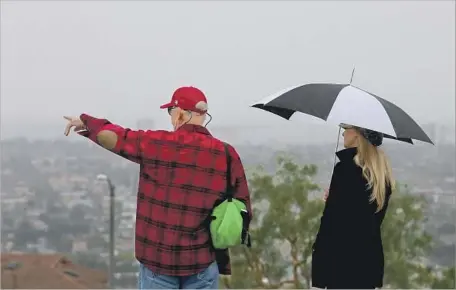  ?? Rick Loomis Los Angeles Times ?? SHOWERS didn’t deter Norbet Nagel of Denver and his sister Susan Gobbel of Riverside from enjoying the view in Signal Hill.