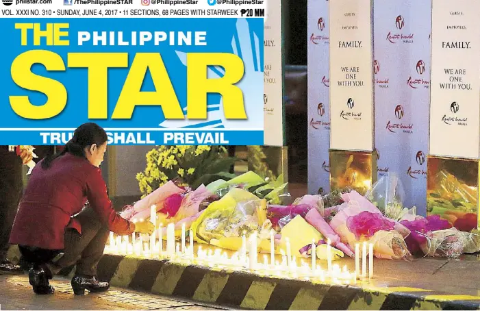  ?? AP ?? Hotel employees light candles and offer flowers at a memorial set up the other night for victims of the attack at the Resorts World Manila complex in Pasay City.