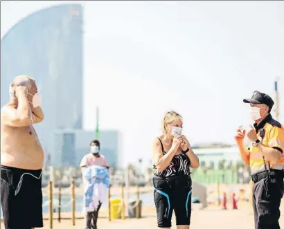  ?? XAVI JURIO ?? Un agente cívico hace ponerse las mascarilla­s a dos bañistas que iban sin ella al salir de la playa
