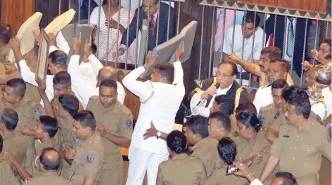  ?? — Reuters ?? Sri Lanka’s police members protect parliament speaker Karu Jayasuriya (C) as he tries to walk to his chair while parliament members who are backing newly appointed Prime Minister Mahinda Rajapakse protest during the parliament session in Colombo.