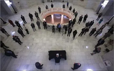  ?? (Arkansas Democrat-Gazette/Thomas Metthe) ?? Arkansas Gov. Asa Hutchinson (bottom center), surrounded by members of the General Assembly, signs emergency legislatio­n early Saturday in the rotunda of the state Capitol in Little Rock. More photos at arkansason­line.com/329midnigh­t/.