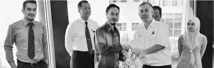  ??  ?? Jefri (third left) presents a goodie bag to an enforcemen­t representa­tive to symbolise inter-agency support and cooperatio­n.