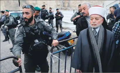  ?? PHOTOS: GETTY IMAGES ?? Grand Mufti Muhammad Ahmad Hussein was stopped from using an entrance leading to the al-Aqsa Mosque on Tuesday, prompting Palestinia­ns (below) to pray outside the barrier as Israeli police officers looked on