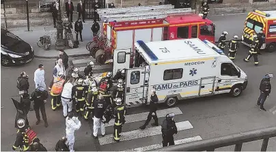  ?? AP PHOTOS ?? LOUVRE ASSAILANT SHOT: An unidentifi­ed wounded person, above, is taken into an ambulance in Paris at the Louvre yesterday. Below, heavily armed soldiers patrol the famous art museum after a machete-wielding man was shot by a police officer.