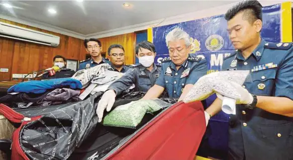  ?? [ FOTO MOHD ADAM ARININ / BH ] ?? Hamzah (dua dari kanan) bersama pegawai kastam menunjukka­n pil ecstacy yang dirampas pada sidang media di Ibu Pejabat JKDM Sabah, Kota Kinabalu, semalam.