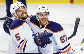  ?? JEFF MCINTOSH / THE CANADIAN PRESS VIA AP ?? Edmonton Oilers center Connor McDavid (right) celebrates his Game 5 overtime goal against the Calgary Flames with defenseman Cody Ceci on Thursday in Calgary, Alberta.