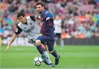  ?? AFP ?? Lionel Messi, right, vies with Valencia’s Daniel Parejo for possession in Barcelona’s 2-1 win yesterday at Camp Nou. Parejo would score a penalty late but Valencia would not find an equaliser