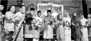  ??  ?? Abang Johari (centre) and others hold the Malay traditiona­l delicacy ‘Ketupat’ to symbolical­ly open the Hari Raya gathering.