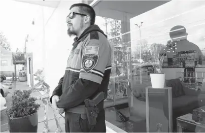  ?? TED S. WARREN/AP ?? Security guard Austin MacMath stands watch April 19 outside a marijuana store in Tacoma, Washington. A surge in robberies is helping fuel a renewed push for federal banking reforms that would make the cash-dependent stores a less appealing target.