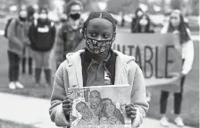  ??  ?? Ninth-grader Graça Jovelino, 16, a recent immigrant from Angola, holds her drawing of Ahmaud Arbery, left, George Floyd, center, and Breonna Taylor, right.