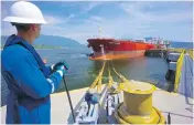  ??  ?? A Kinder Morgan Canada worker assists with a tanker departure in Burrard Inlet at the Westridge Marine Terminal in Burnaby.