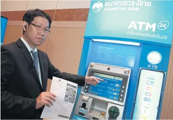  ?? SOMCHAI POOMLARD ?? A Krungthai Bank staff member shows how to pay traffic fines via the bank’s ATMs, an e-payment service the bank is offering in cooperatio­n with the Royal Thai Police.
