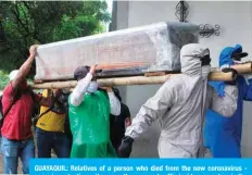  ?? —AFP ?? GUAYAQUIL: Relatives of a person who died from the new coronaviru­s some in protective suits- carry the wrapped coffin inside a cemetery in the north of Guayaquil, Ecuador.
