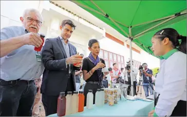  ?? HONG MENEA ?? Agricultur­e ministry undersecre­tary of state Im Rachna (centre right) and several EU specialist­s examine the drinks made by students at the University of Kratie earlier this month.