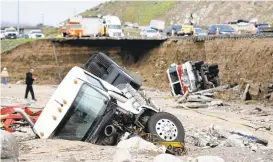  ?? DAVID PARDO/THE DAILY PRESS VIA ASSOCIATED PRESS ?? Officials on Saturday look over the scene where a tractor-trailer fell Friday from southbound Interstate 15 after part of the freeway collapsed due to heavy rain in the Cajon Pass.