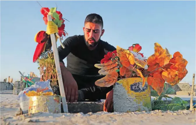  ??  ?? KOBANI: A Kurdish man mourns over his friend’s grave who was killed while fighting against Islamic State militants in Raqqa, at a cemetery. — AP