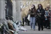  ?? ALASTAIR GRANT — THE ASSOCIATED PRESS ?? Two people carry flowers to place in front of the gate at Buckingham Palace in London on Friday. Buckingham Palace officials say Prince Philip, the husband of Queen Elizabeth II, has died. He was 99.