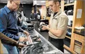  ?? JEWEL SAMAD/GETTY-AFP ?? An employee shows handguns at a shooting range last month in Randolph, N.J. President Barack Obama seeks to curb gun violence by expanding background checks.