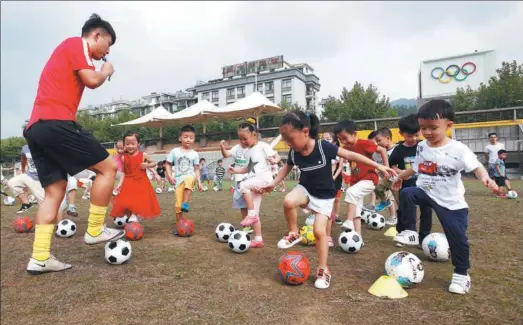  ?? XU JUNYONG / FOR CHINA DAILY ?? Kindergart­en kids in Tonglu county, Zhejiang province enjoy their first soccer lesson under the guidance of a profession­al coach in September.