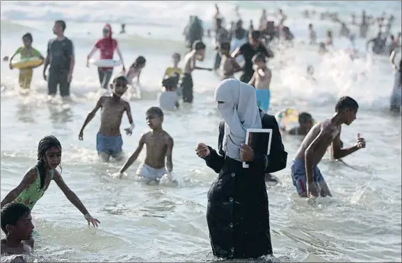  ?? MENAHEM KAHANA / AFP ?? Una chica palestina, cubierta con velo integral, se refresca en el mar en una playa de Tel Aviv, en agosto del 2013
