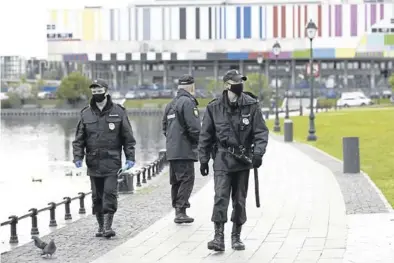  ?? AP / ALEXANDER ZEMLIANICH­ENKO ?? Policías rusos con máscaras faciales patrullan en las inmediacio­nes del estanque Ostankino, en Moscú.