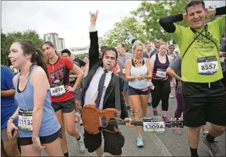  ?? JAY JANNER/AMERICAN-STATESMAN ?? Ravner Salinas, dressed as Angus Young of AC/DC, crosses the finish line at the Statesman Capitol 10,000 April 10, 2016.