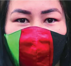  ?? REUTERS ?? Una mujer afgana con una mascarilla con la bandera nacional en Nueva Delhi