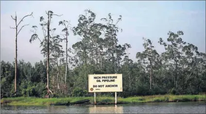  ?? Photo: Akintunde Akinleye/Reuters ?? Oil is not well: A Shell warning sign along Nembe creek in Nigeria’s oil state of Bayelsa. The company is mired in a $1.1-billion bribery scandal in the oil-rich country.