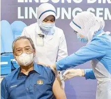  ?? REUTERS ?? Malaysia’s Prime Minister Muhyiddin Yassin receives the first dose of Pfizer-BioNTech COVID-19 vaccine at a clinic in Putrajaya yesterday.