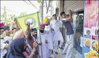  ?? SAMEER SEHGAL /HT ?? Farmers forcing a trader to open his shop in Amritsar on Saturday.