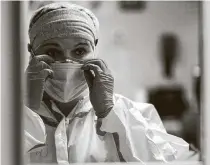  ??  ?? Nurse Christina Mathers adjusts her surgical mask, which sits on top of an N95 mask, before checking on her patients.