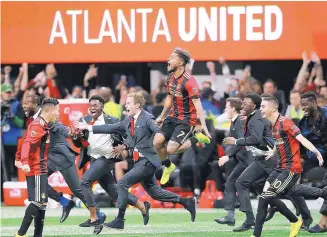  ?? CURTIS COMPSON/ASSOCIATED PRESS ?? Atlanta United’s Josef Martinez (7) leaps in the air and Miguel Almiron (10) joins in to celebrate the team’s MLS title-game victory over Portland on Saturday night.