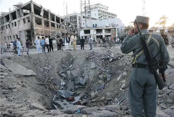  ?? — THE ASSOCIATED PRESS ?? Security forces stand next to a crater created by a massive explosion near the Canadian Embassy in Kabul, Afghanista­n, on Wednesday. The suicide truck bomb hit a highly secure diplomatic area of Kabul killing scores of people and wounding hundreds more.