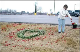  ?? (NWA Democrat-Gazette/Annette Beard) ?? Mechel Wall of Wallflower Farms scattered red rose petals around a heart-shaped floral arrangment on the lawn in front of Walmart Neighborho­od Market as a memorial to covid-19 victims on Monday.