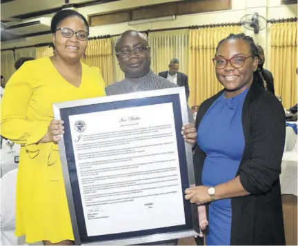  ?? ?? Press Associatio­n of Jamaica Secretary and Observer Associate Editor - News/health Kimberley Hibbert (left) shares lens with Observer Pre-press Technician Ian Watkis (centre) after presenting him with a framed citation at the Press Associatio­n of Jamaica Veterans’ Luncheon on Wednesday at Alhambra Inn in St Andrew. Also pictured is Shantaee Lewis, senior public affairs and digital media specialist at J Wray and Nephew, sponsor of the luncheon.