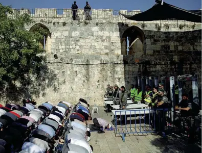  ??  ?? In preghiera Poliziotti israeliani davanti ai metal detector alla Spianata delle Moschee. Di fronte, musulmani in preghiera (Ap)