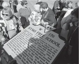  ?? STEPHEN M. KATZ/STAFF PHOTOS ?? Members of the Virginia Society of the Colonial Dames 17th Century gather around a historical marker that memorializ­es the Syms Free School on Friday at the NASA Langley Research Center.