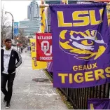  ?? STEVE SCHAEFER / SPECIAL TO THE AJC ?? LSU Tigers fan Branden Richard looks over the team banners out front of the Sports Mania popup store near the CNN Center on Friday.