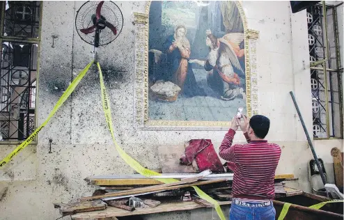  ?? AFP / GETTY IMAGES ?? An Egyptian uses his cellphone to take photos of the destructio­n, debris, and bloodstain­s on the walls and icon murals inside the Mar Girgis Coptic church in Tanta, 120 kilometres north of Cairo, at which a bomb blast Sunday struck worshipper­s...