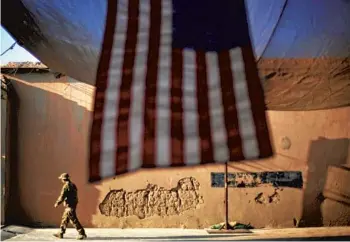  ?? DAVID GOLDMAN/AP 2011 ?? A U.S. Army soldier walks past an American flag in Afghanista­n’s Kunar province on the 10th anniversar­y of the Sept. 11 attacks. After 20 years, the U.S. formally started the final phase of withdrawin­g from the country Saturday.