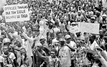  ?? — AFP photo ?? Protesters carry placards while they march shouting slogans as they call for reforms during an anti-government rally in Lome.