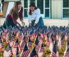  ?? Tom Cruze/ ?? Students Kathryn Brooks, left, and Nina Salazar straighten some of the 2,981 flags on display Friday at Trinity Classical Academy in Santa Clarita. Young Americans for Freedom placed the flags to honor the the 2,977 lives lost on Sept. 11, 2001, and...