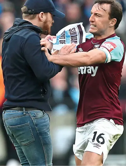  ?? OFFSIDE ?? Anger management: Hammers captain Mark Noble restrains a pitch invader on Saturday