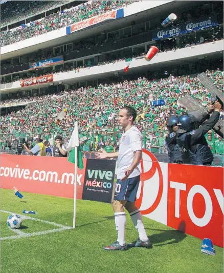  ?? Donald Miralle Getty Images ?? THE POLICE ARE protected by riot shields, but U.S. star Landon Donovan stands alone as he is pelted with cups of water, beer and other items as he attempts a corner kick during a World Cup qualifying match at Mexico City’s Azteca Stadium in 2009.