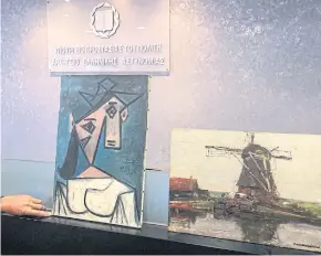  ??  ?? BACK IN SAFE HANDS: A recovered painting of Picasso titled ‘Head of a Woman’ flanked by a painting by Dutch painter Piet Mondrian, in Athens.