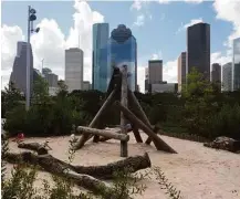  ?? Diane Cowen / Houston Chronicle ?? The downtown skyline provides a backdrop for play areas such as this sand pit with a teepee of logs at the play park.
