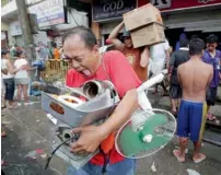  ?? AP ?? A man reacts after getting supplies from a grocery that was stormed by people and, right, cars and debris float along a river. —