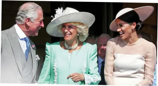  ??  ?? Happy family: Meghan laughs along with Charles and Camilla yesterday as she settles in to her new role with ease