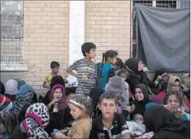  ?? Bram Janssen ?? The Associated Press Women and children from Hawija sit Tuesday outside a Kurdish screening center in Dibis, Iraq. On Thursday, Iraqi Prime Minister Haider al-abadi said troops have driven IS militants from the town of Hawija, one of the extremists’...
